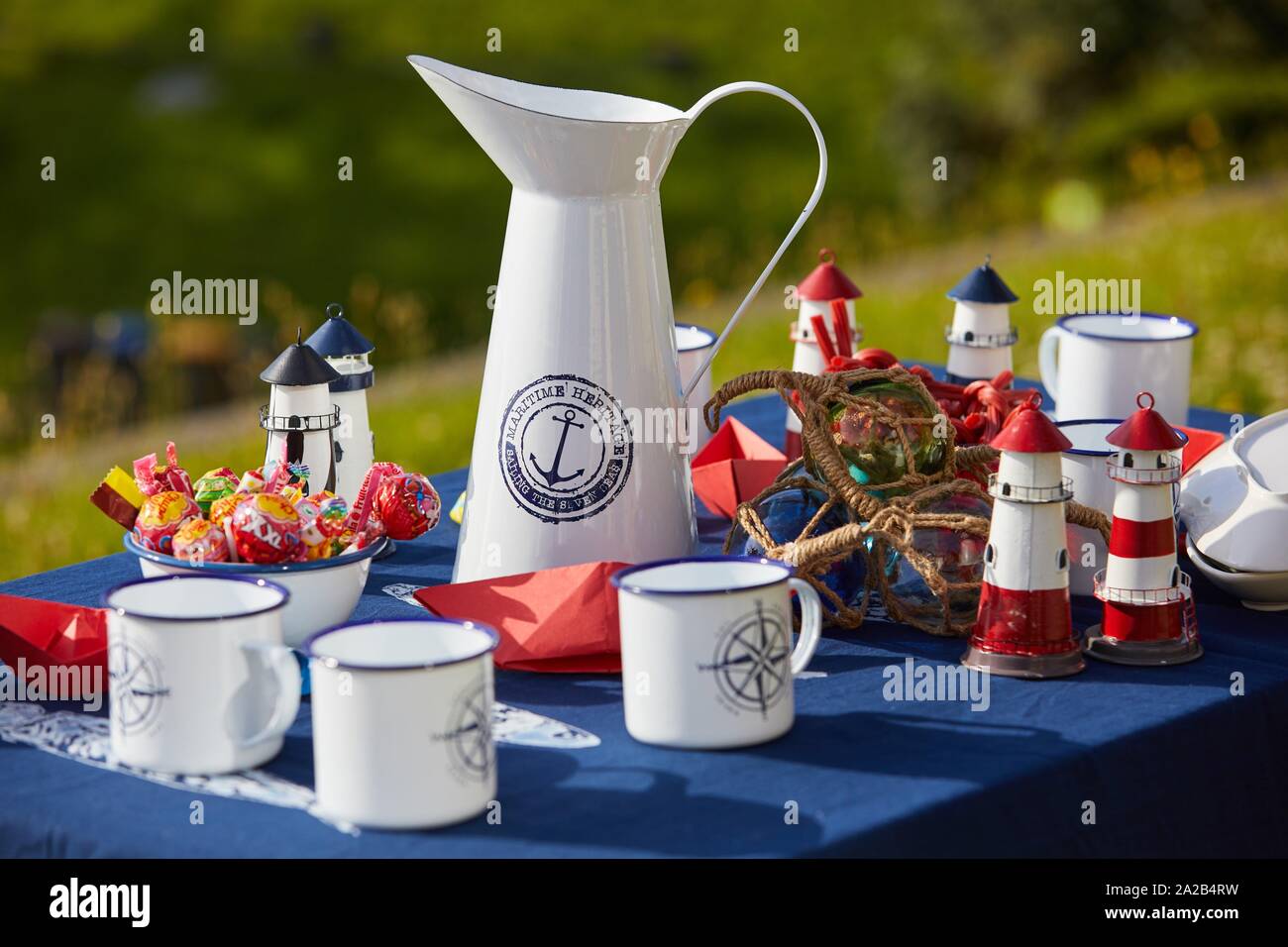 Tabla con jarra y tazas, dulces y marinero detalles Foto de stock