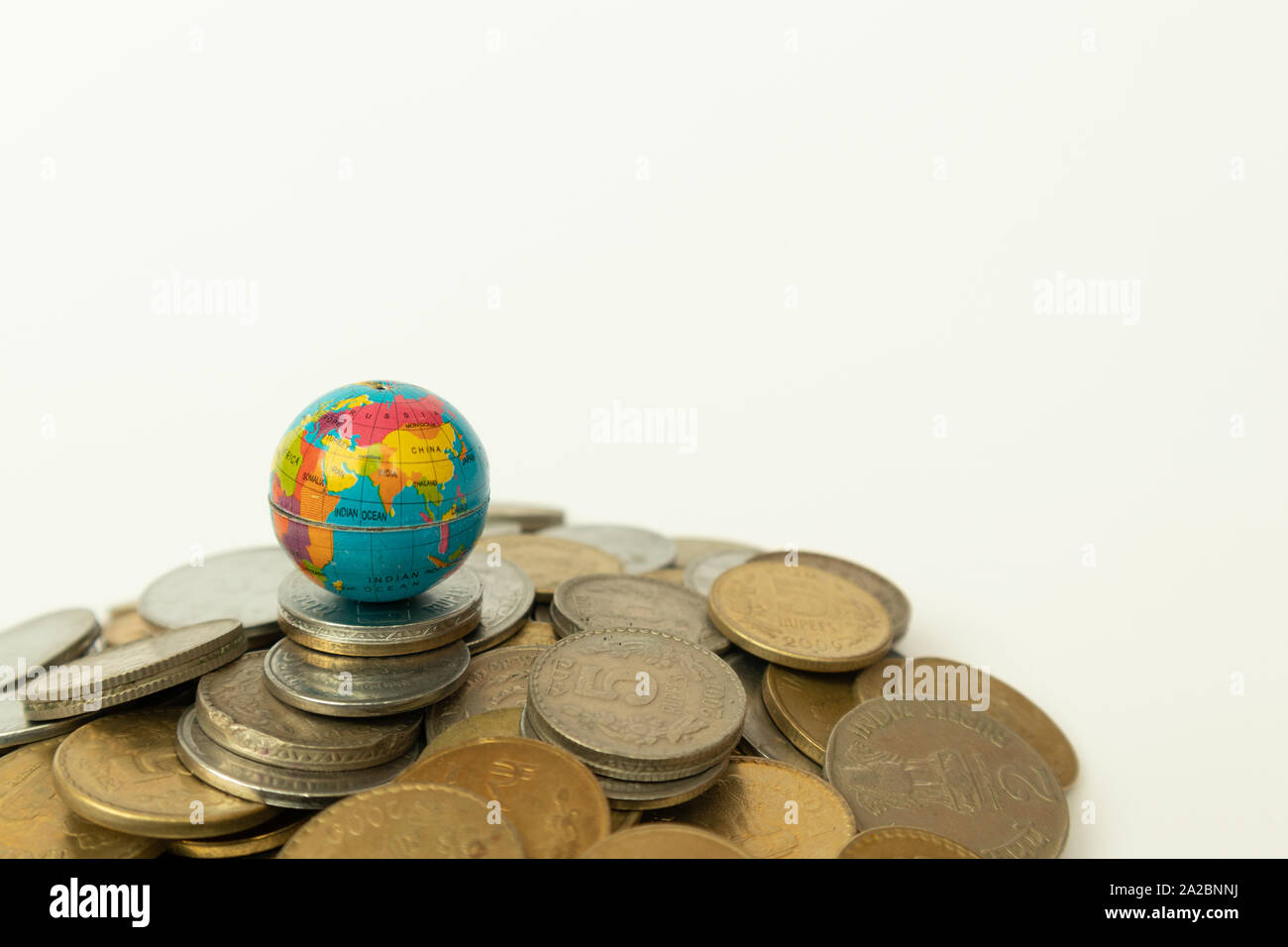 Concepto de todo el mundo están en el dinero, la pila de monedas indias en Globo por encima de las monedas sobre el aislamiento del fondo. Foto de stock
