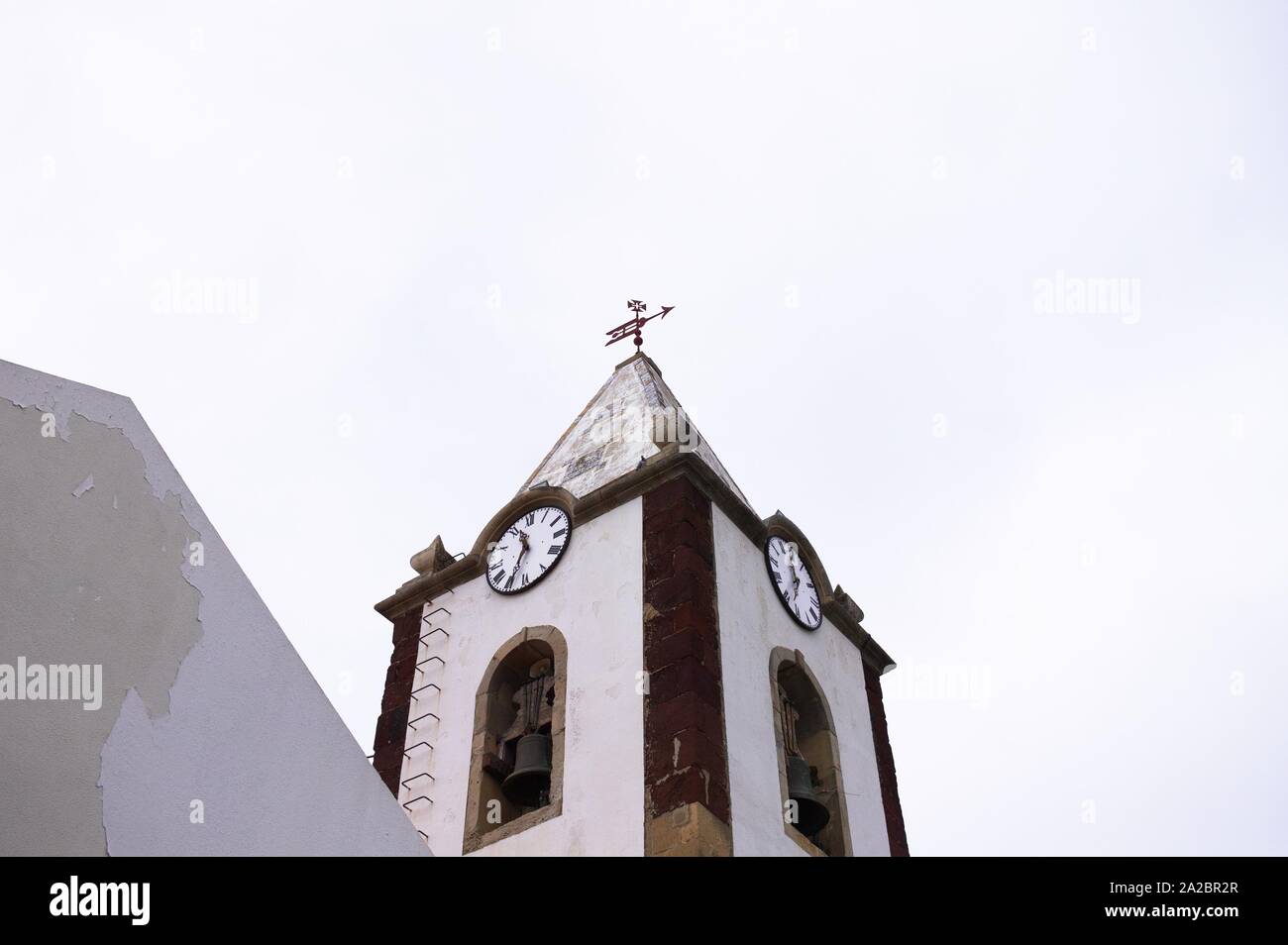 Reloj y campanario de un edificio religioso con un crucifijo en la parte superior (Madeira, Portugal) Foto de stock