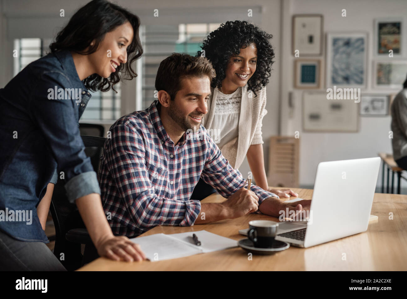 Sonriente, grupo de diseñadores que trabajan juntos en una oficina portátil Foto de stock