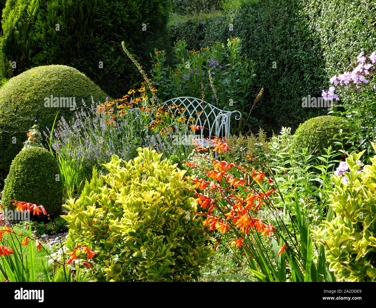 English country garden con flores blancas y rejas decorativas bench Foto de stock