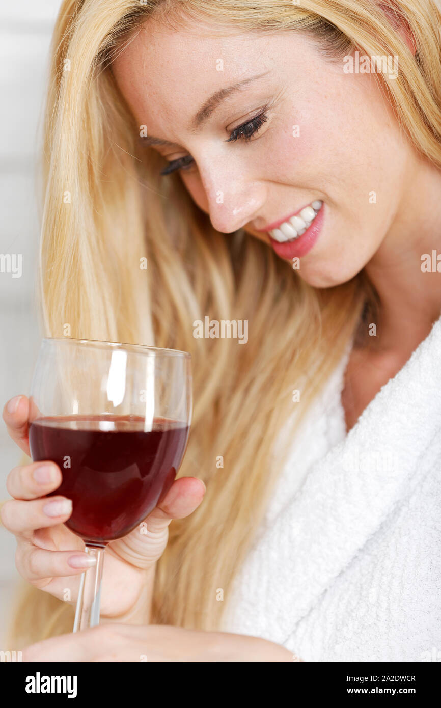 Hermosa joven con una túnica blanca disfrutando de una copa de vino tinto Foto de stock