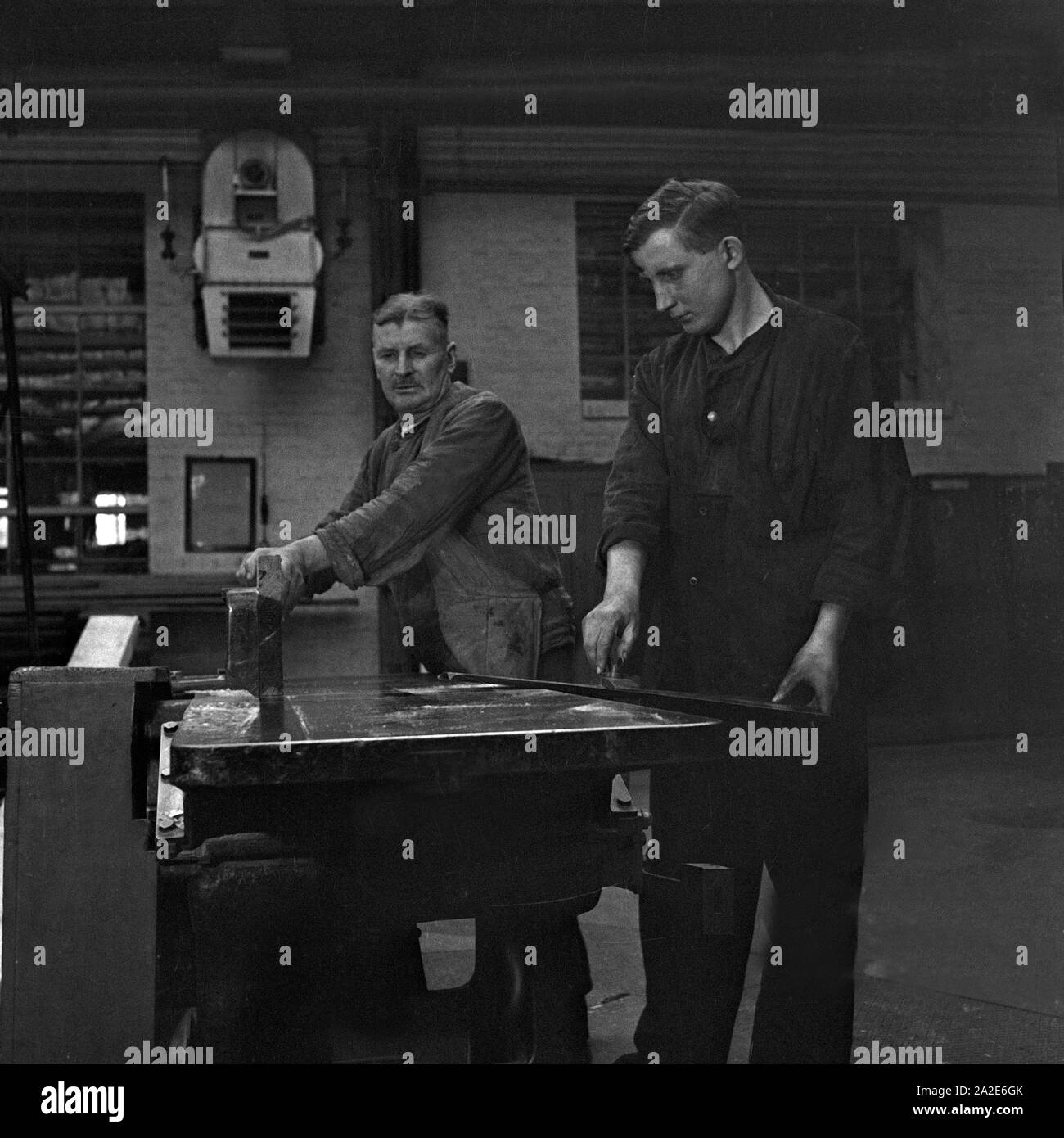 Zwei Arbeiter en einem Walzenwerk un ihrem Arbeitsplatz, Deutschland 1930er Jahre. Dos trabajadores en su lugar de trabajo en una fábrica de hilo de rodillo, Alemania 1930. Foto de stock