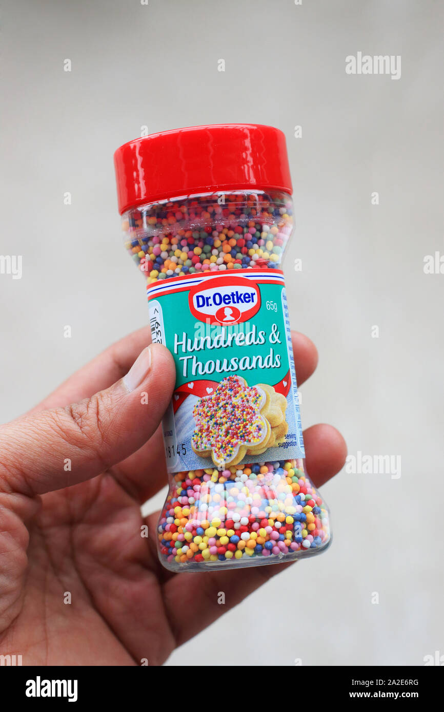 Mano sujetando el Dr. Oetker cientos y miles de coloridas comestibles sprinkles Foto de stock