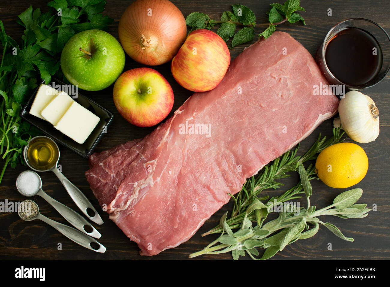 Lomo de cerdo asado con manzana y hierbas ingredientes: carne de cerdo asada  deshuesada cruda, frutas, verduras y hierbas utilizadas para hacer un plato  de lomo de cerdo asado Fotografía de stock -