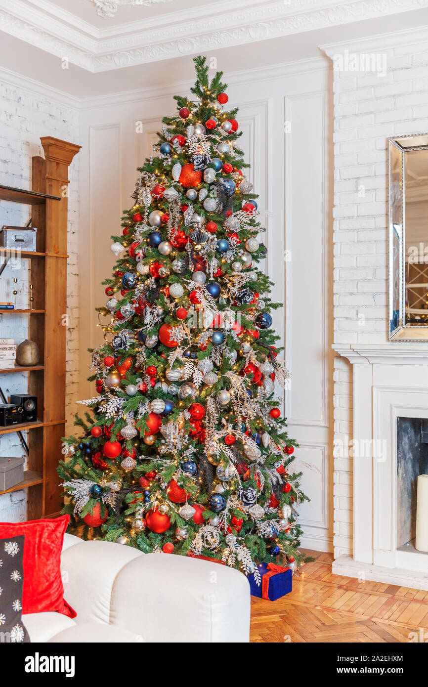 Clásico de Año Nuevo de navidad decorado salón interior del árbol de Año  Nuevo. Árbol de Navidad con adornos de plata y ornamento rojo. Moderno  diseño interior de estilo clásico blanco apartamento.
