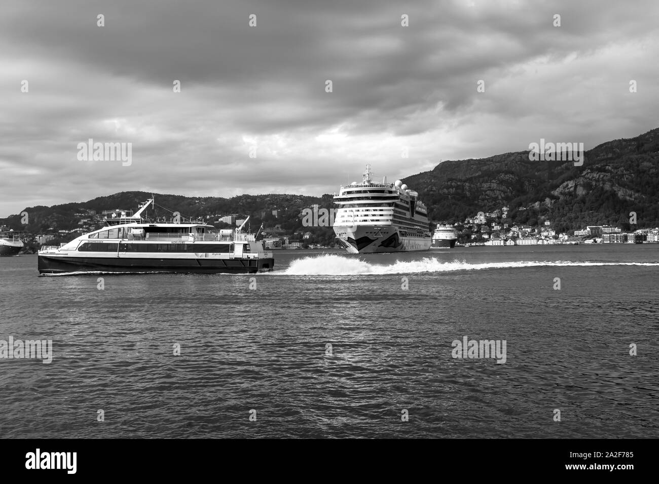 Crucero AIDAluna partiendo desde el puerto de Bergen, Noruega. Catamarán de alta velocidad para pasajeros Ekspressen pasando por delante. Foto de stock