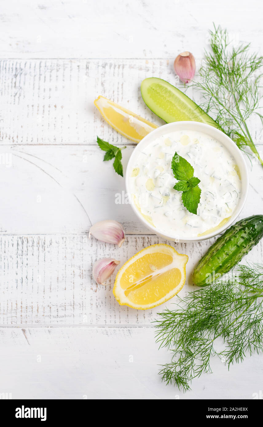 Salsa dip griego o vendaje tzatziki decorado con aceite de oliva y menta sobre mesa de madera blanca Foto de stock