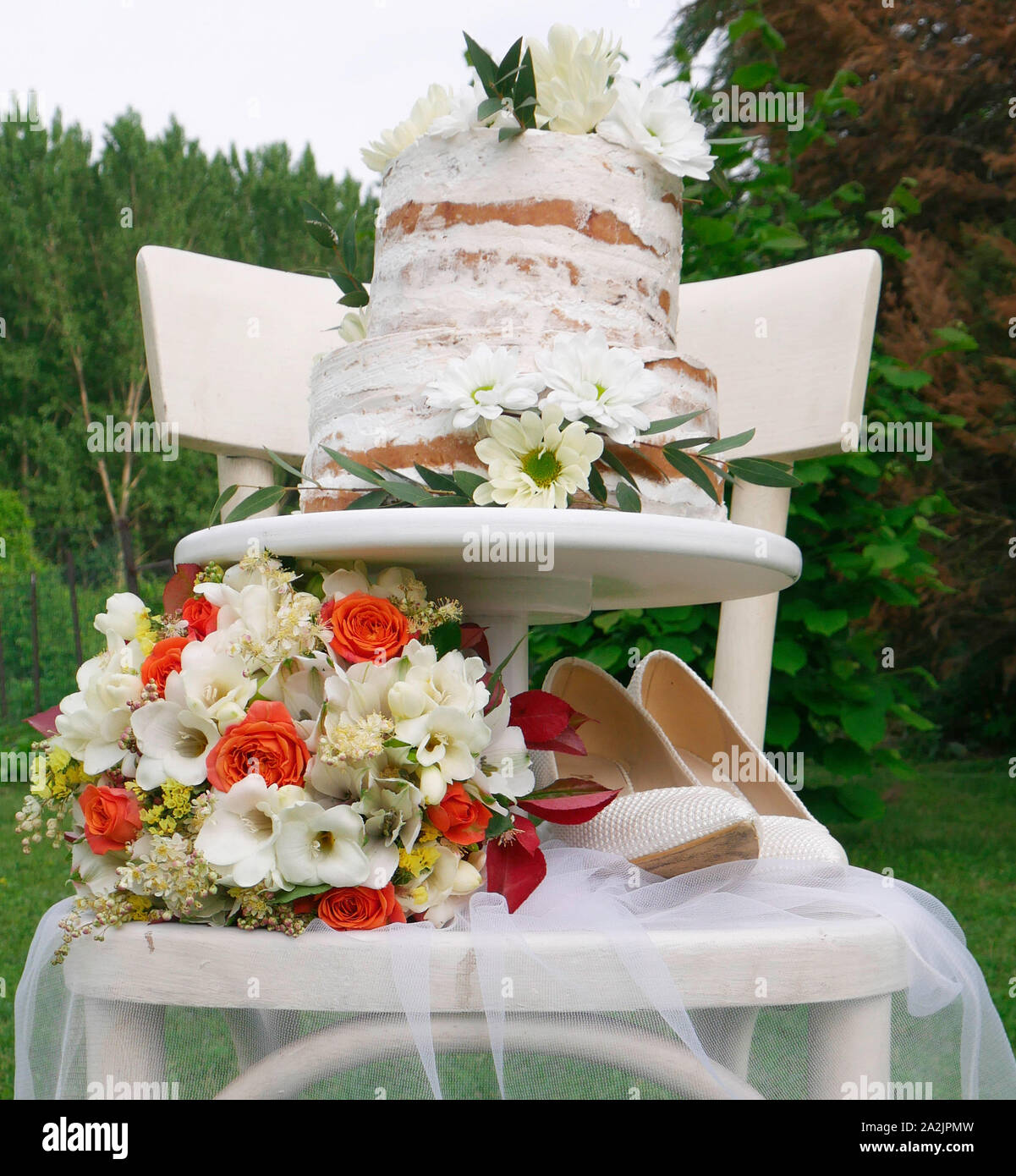Novias zapatos blancos y pastel de boda de dos niveles en una silla de  madera Fotografía de stock - Alamy