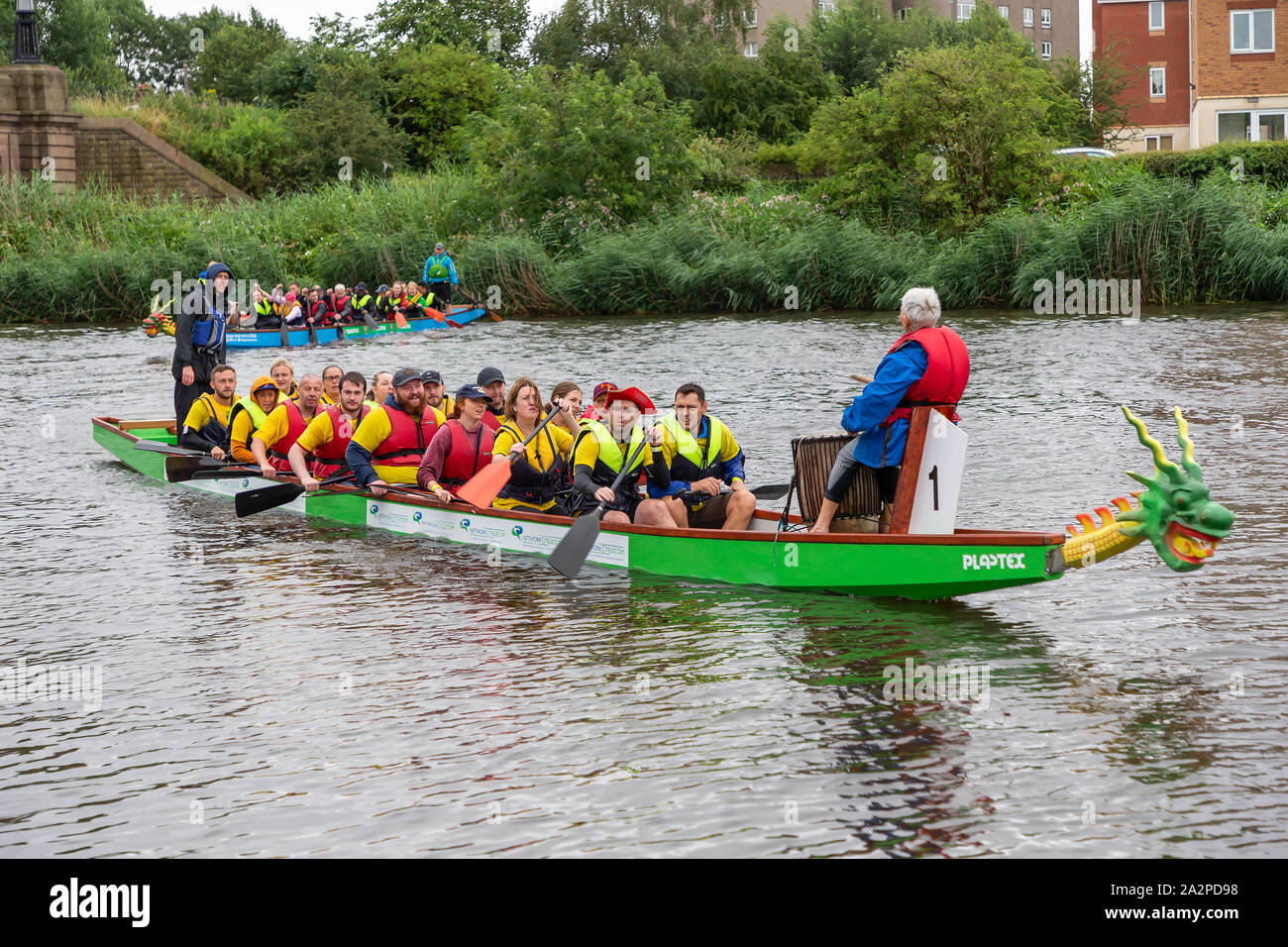 Los equipos vienen al borde del río al final de la carrera de botes dragón 2019 en ayuda de San Rocco's Hospice, celebrado en el Club de Remo en Warrington, Cheshire, Engla Foto de stock