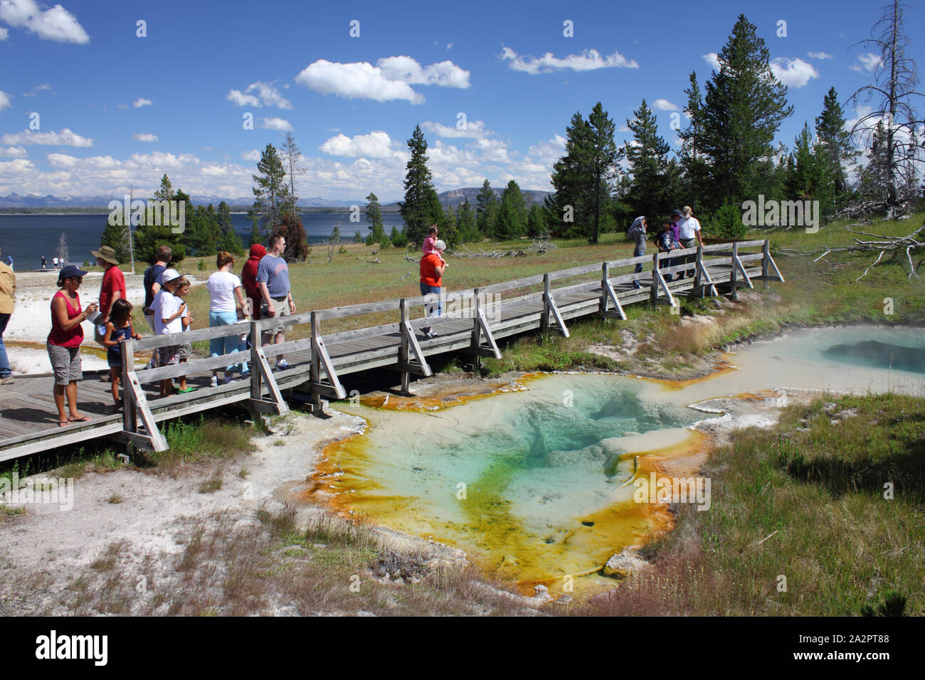 Los turistas que caminan a lo largo de junta sobre bacterias extremófilos escurrimiento, junto al lago, el muelle, el Parque Nacional Yellowstone, Wyoming, EE.UU. Foto de stock