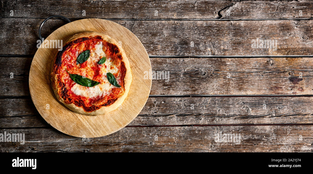 Casero italiano fresco Pizza Margherita con albahaca en fondo rústico. Foto de stock