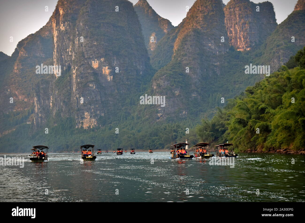 Parque del río Li lanchas turísticas debajo de altos picos montañosos, Guangxi, China Foto de stock
