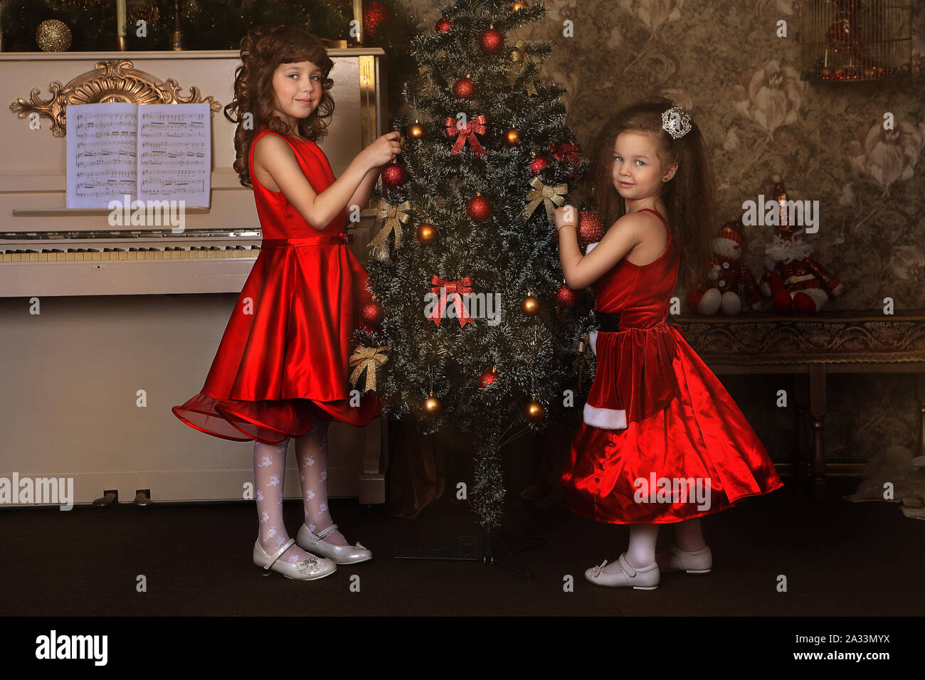 Dos niñas en vestidos rojos Decorar un árbol de Navidad Fotografía de stock  - Alamy