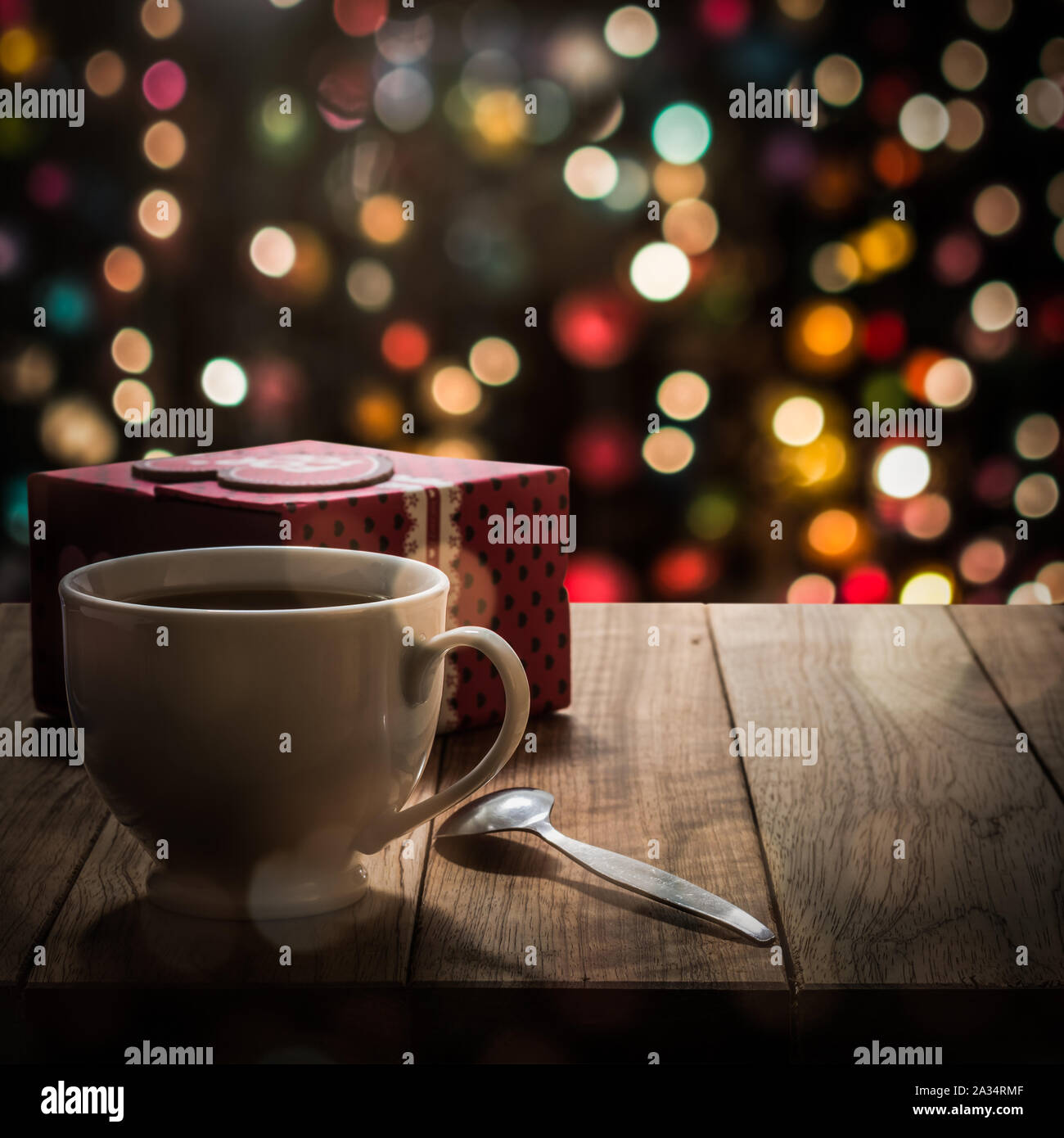 Café caliente con caja de regalo sobre la mesa de madera en colores de fondo bokeh Foto de stock