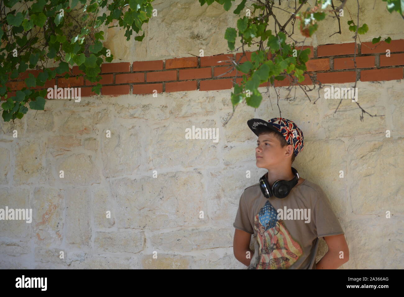 Un retrato de un joven con auriculares en ropa casual posando sobre la  pared de ladrillo. Moda para varones adolescentes Fotografía de stock -  Alamy