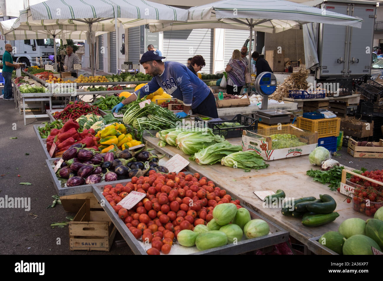 Un puesto en el mercado trader organizar sus productos en Ostuni Mercado el sábado Foto de stock