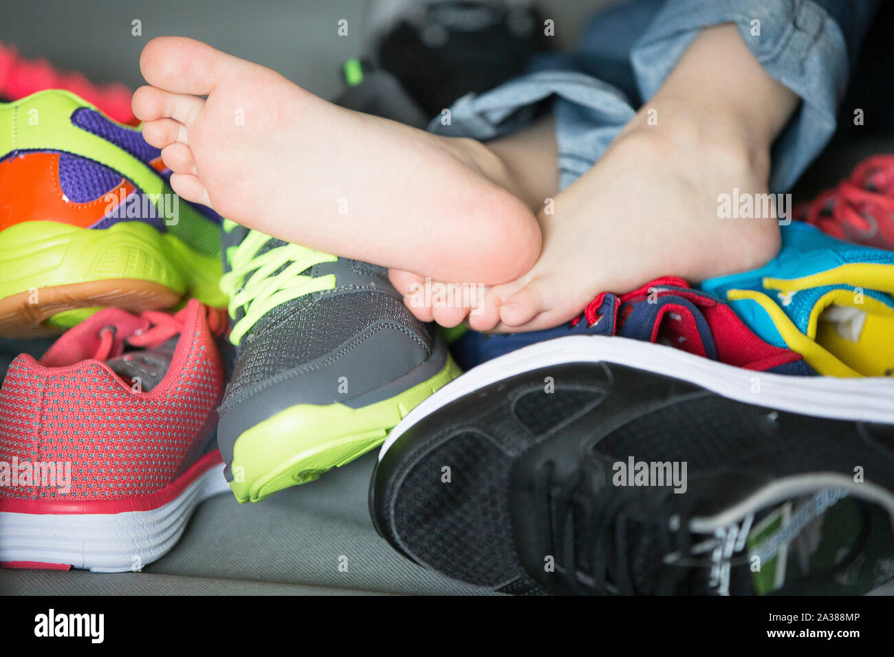 Los pies descalzos en un montón de zapatos. Children's pie sobre el fondo  de las zapatillas de deporte. Pies y calzado Fotografía de stock - Alamy