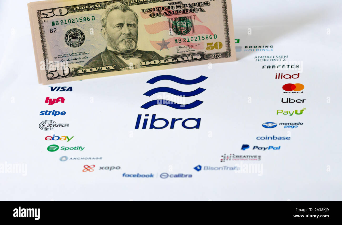 El logotipo de la Asociación Libra en papel folleto y billetes de dólar estadounidense. Ilustrativa para Facebook moneda mundial Libra que opuestos el dinero fiat Foto de stock