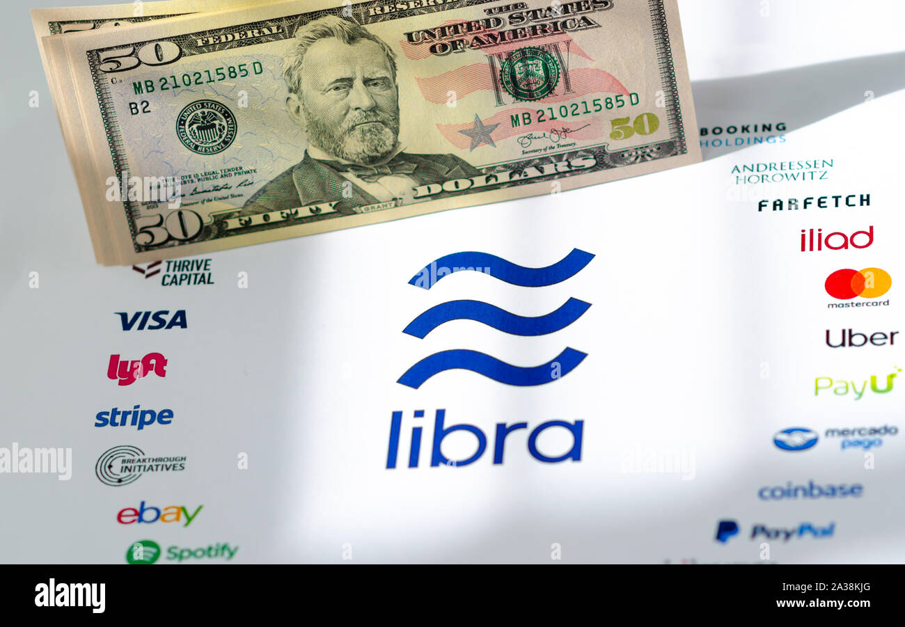 El logotipo de la Asociación Libra en papel folleto y billetes de dólar estadounidense. Ilustrativa para Facebook moneda mundial Libra que opuestos el dinero fiat Foto de stock