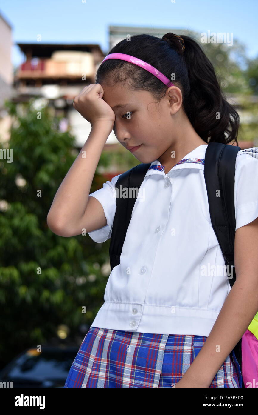 Niña de la escuela diversas preocupaciones y vistiendo uniforme escolar con libros Foto de stock