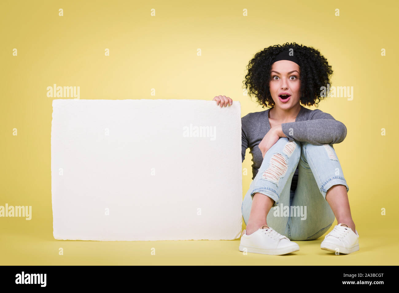 Sorprendido mujer sosteniendo un letrero blanco Foto de stock