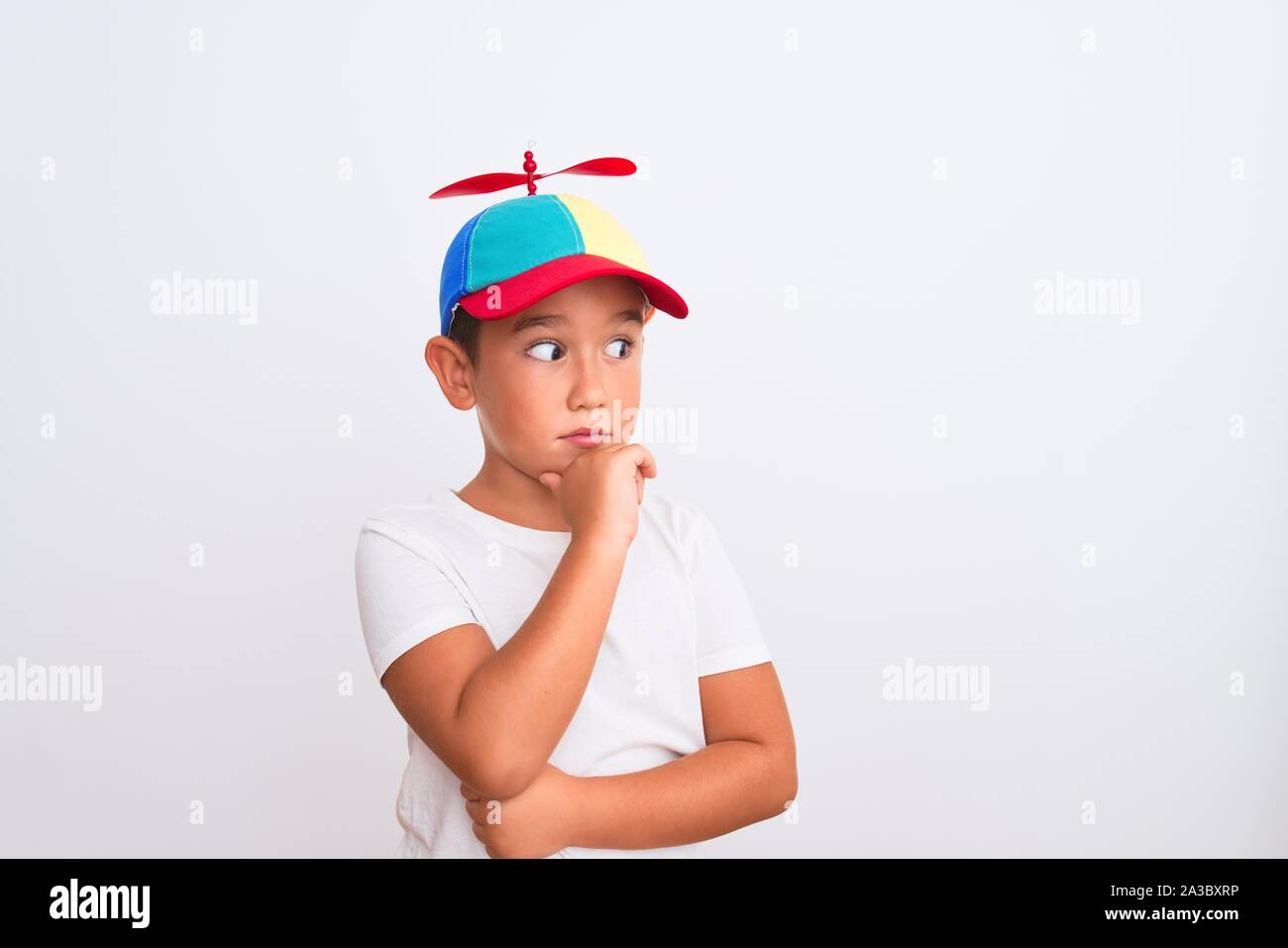 Hermoso niño niño usando fanny colorido con hélice aisladas sobre fondo con la mano en la barbilla, pensativo en cuestión expressi Fotografía de stock - Alamy