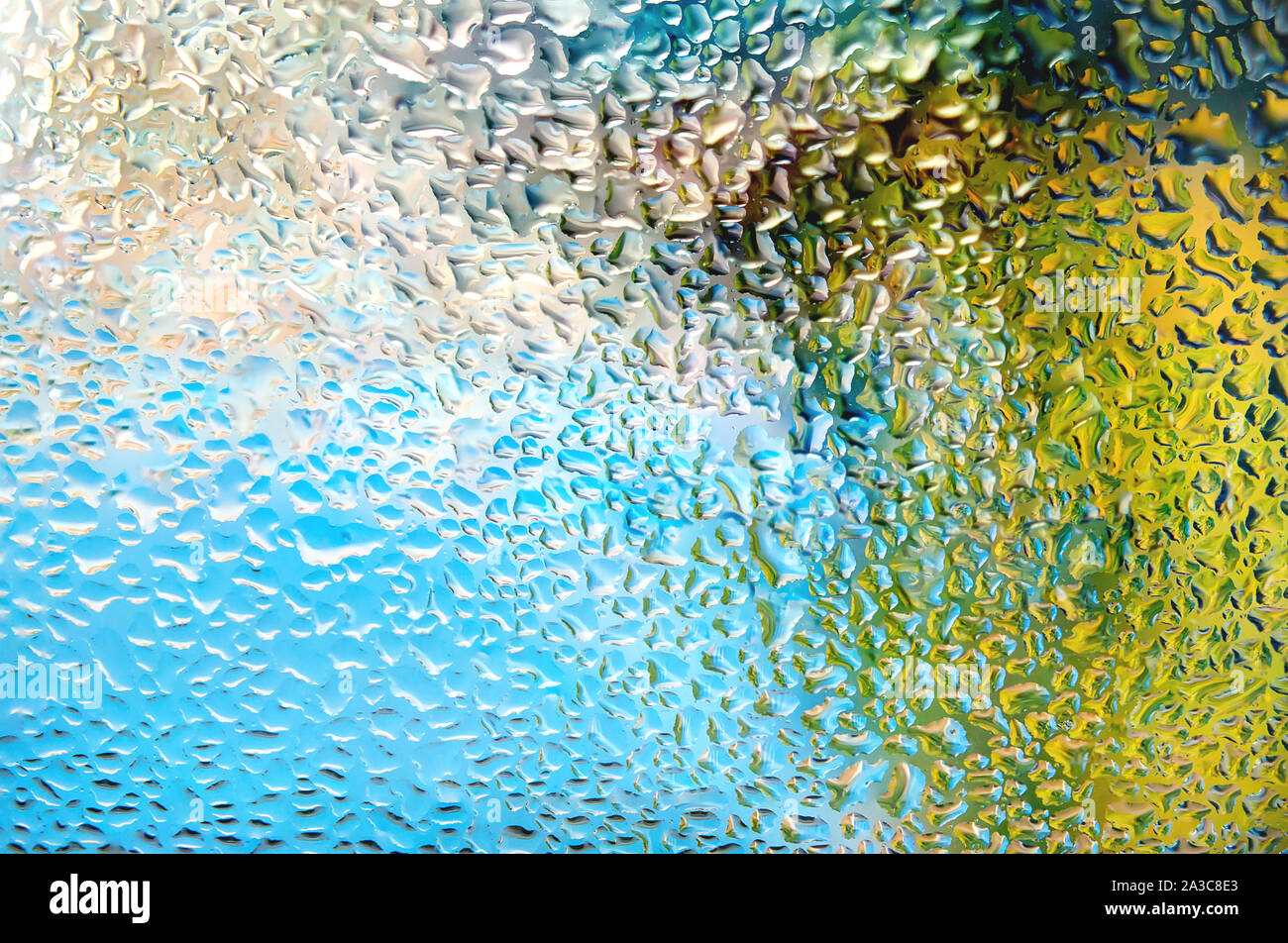 Las gotas de lluvia en el cristal con colores vibrantes borrosa fondo abstracto multicolor. Foto de stock