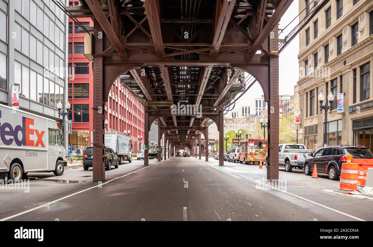Chicago, Illinois, Estados Unidos, 9 de mayo de 2019. El tráfico en la calle debajo y al lado de un puente de metal con columnas. Transporte en la ciudad de fondo. Foto de stock