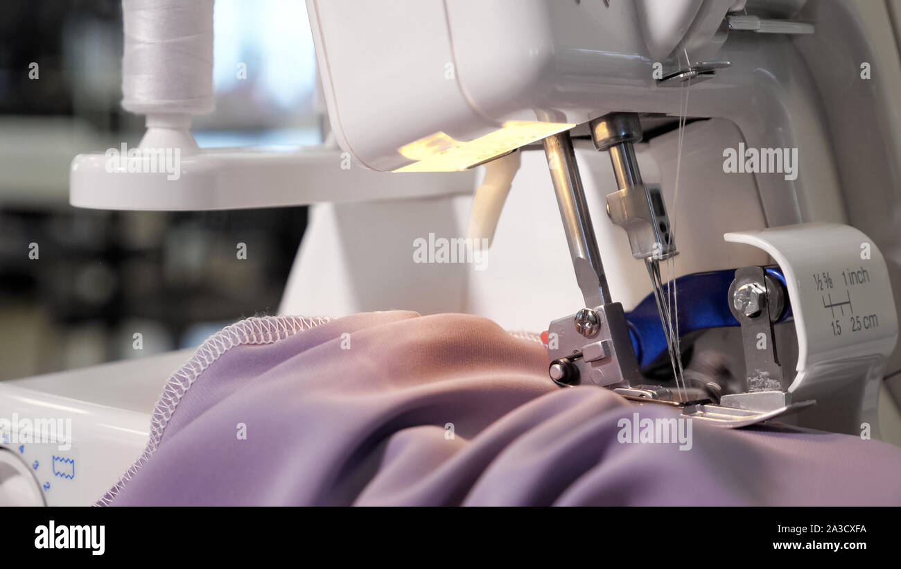 Borde de tejido tejido de procesamiento. Costurera trabajando en la máquina  de coser haciendo puntadas costuras con puntadas rectas en tela morada,  manos closeup. Ropa sastrería fabricación Fotografía de stock - Alamy