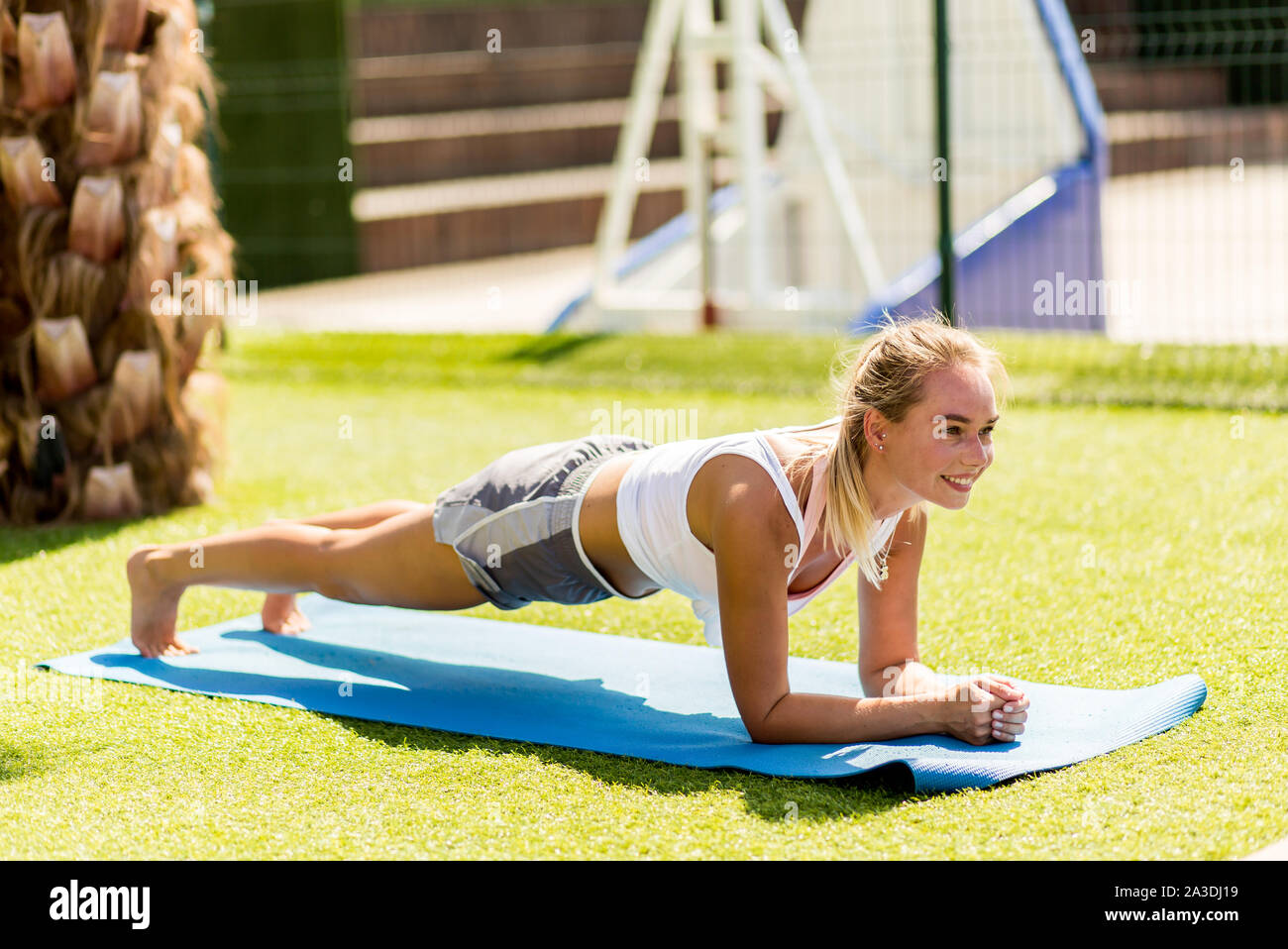 Mujer deportiva atractiva con ropa deportiva blanca usando bloques de yoga  mientras hace tablones laterales en la alfombra de yoga. yoga en casa.