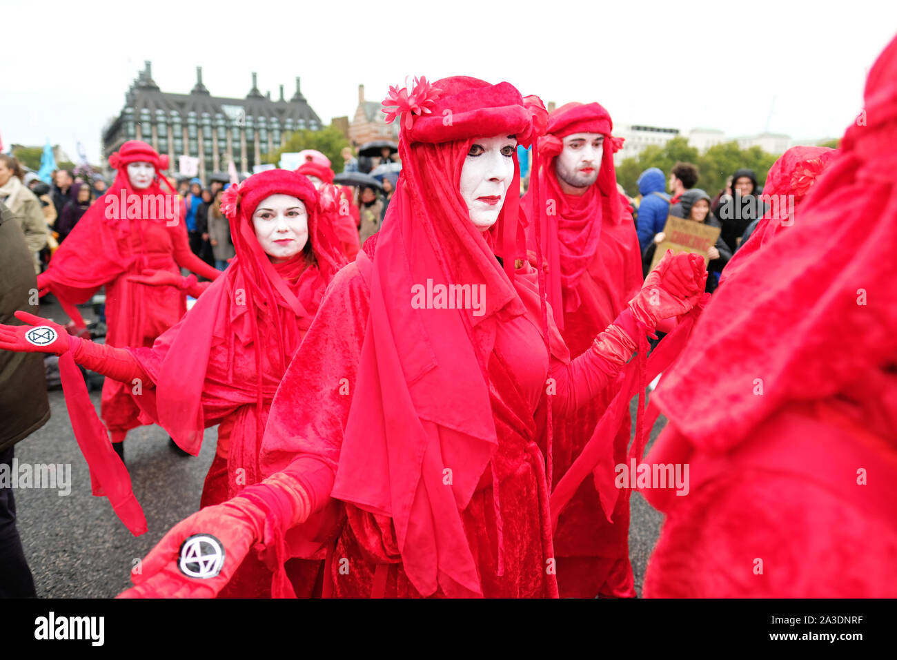 Westminster, Londres, Reino Unido - El lunes 7 de octubre de 2019 - La Extinción rebelión XR Brigada Roja bailarines desfilan en Westminster Bridge en el viento y la lluvia en el día 1 de la XR protesta. Foto Steven Mayo / Alamy Live News Foto de stock