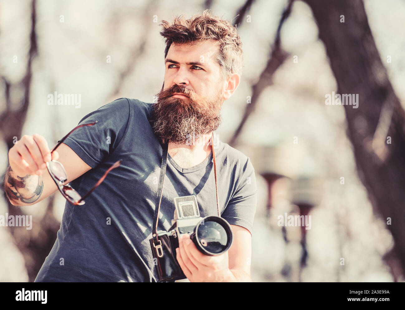 Equipo fotográfico. hipster hombre en gafas de sol. Hipster maduro con  barba. Hombre Barbado. brutal con la cámara del fotógrafo de la naturaleza.  foto reportero o periodista. Periodista de éxito Fotografía de