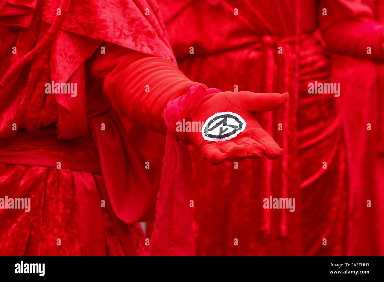 Londres, Reino Unido. 07 Oct, 2019. Un manifestante de extinción movimiento rebelde muestra un símbolo del grupo durante la manifestación. Crédito: Sopa de imágenes limitado/Alamy Live News Foto de stock