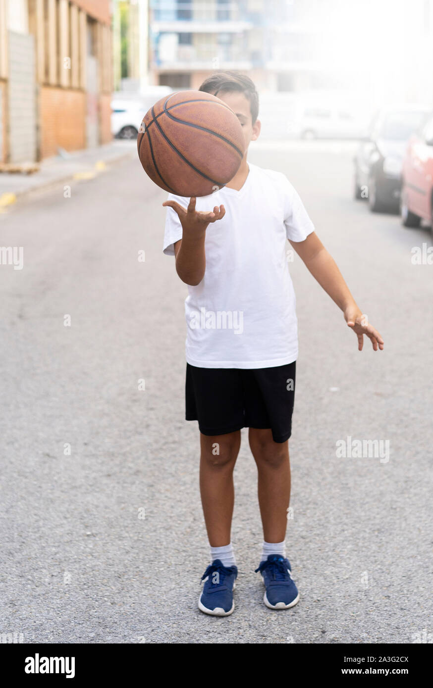 Kid jugar al baloncesto solo en una calle corte Foto de stock