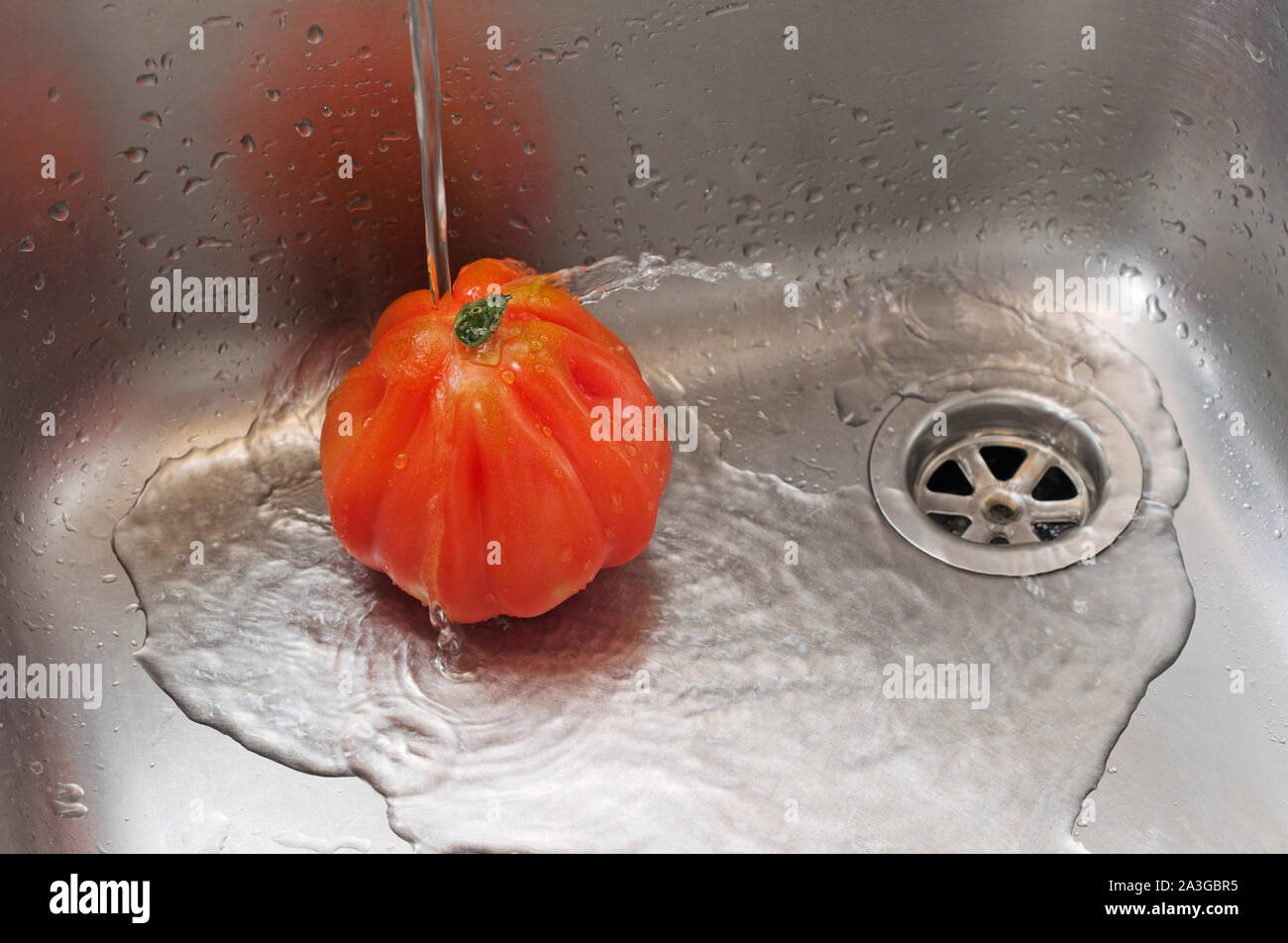 Un enjuague bajo el grifo de agua de tomate Foto de stock