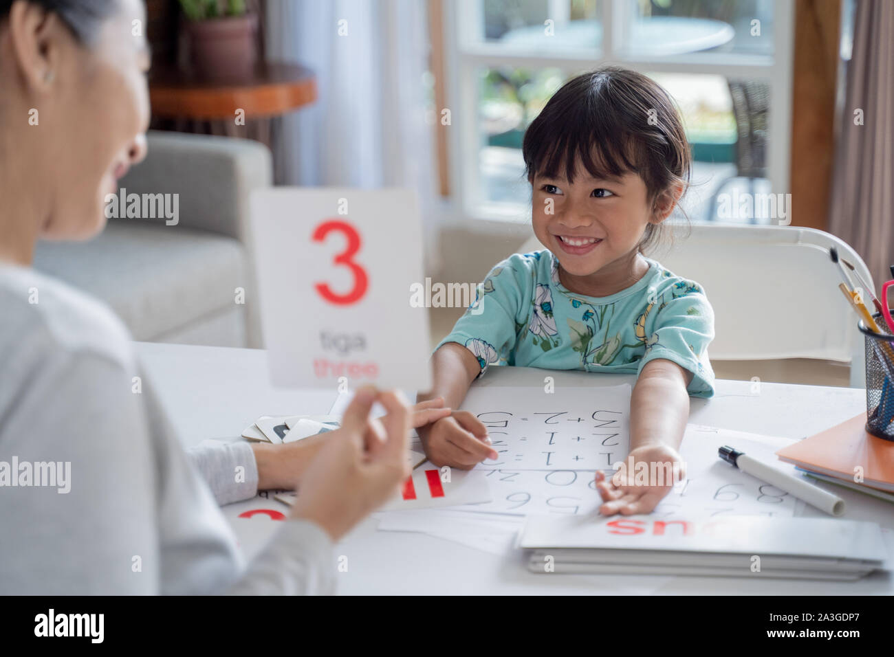 Niño feliz aprendiendo y estudiando, junto con sus padres en casa. homeschooling actividad Foto de stock