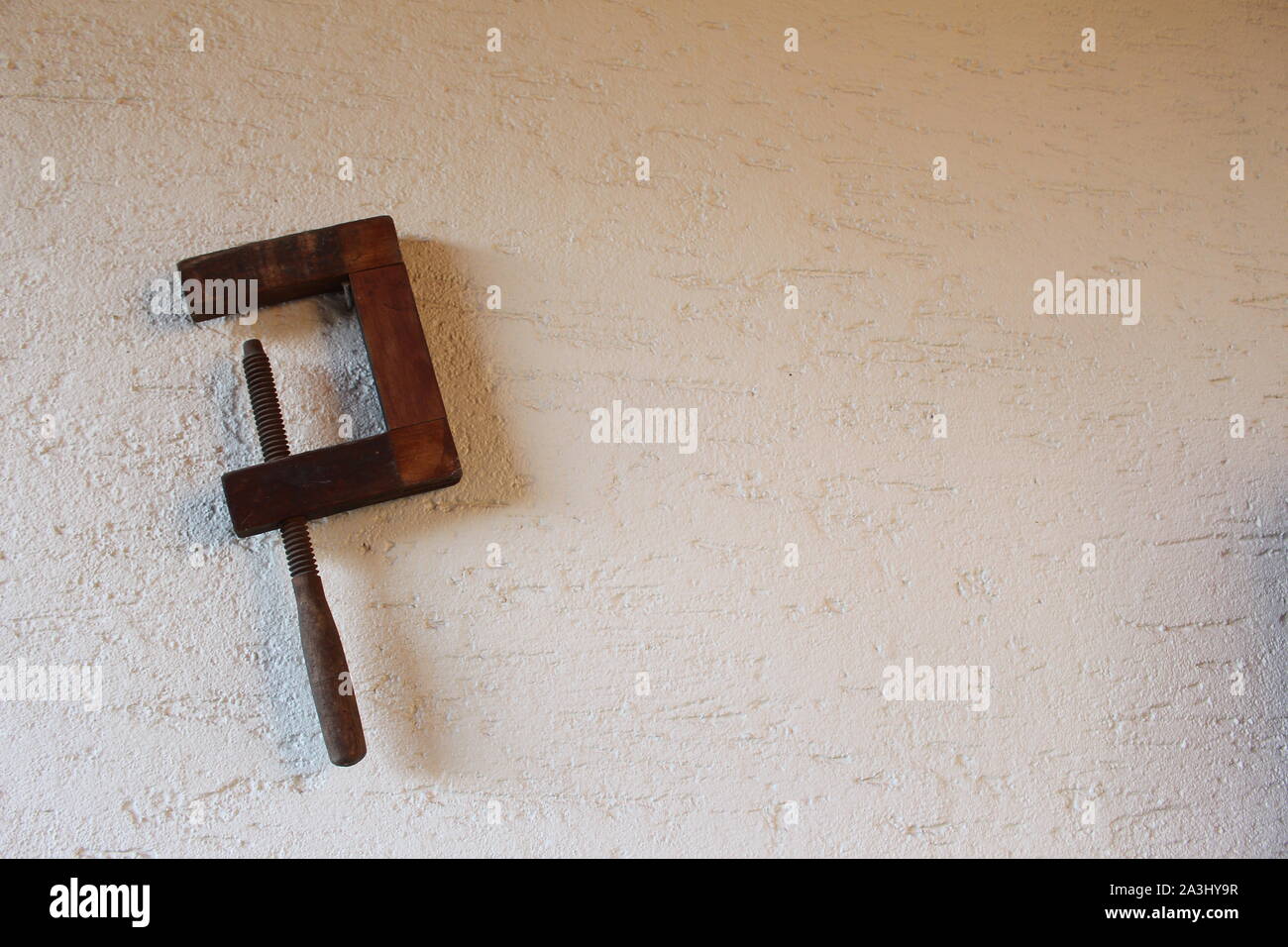 Abrazadera de tornillo de madera antiguos colgado en una pared. Foto de stock