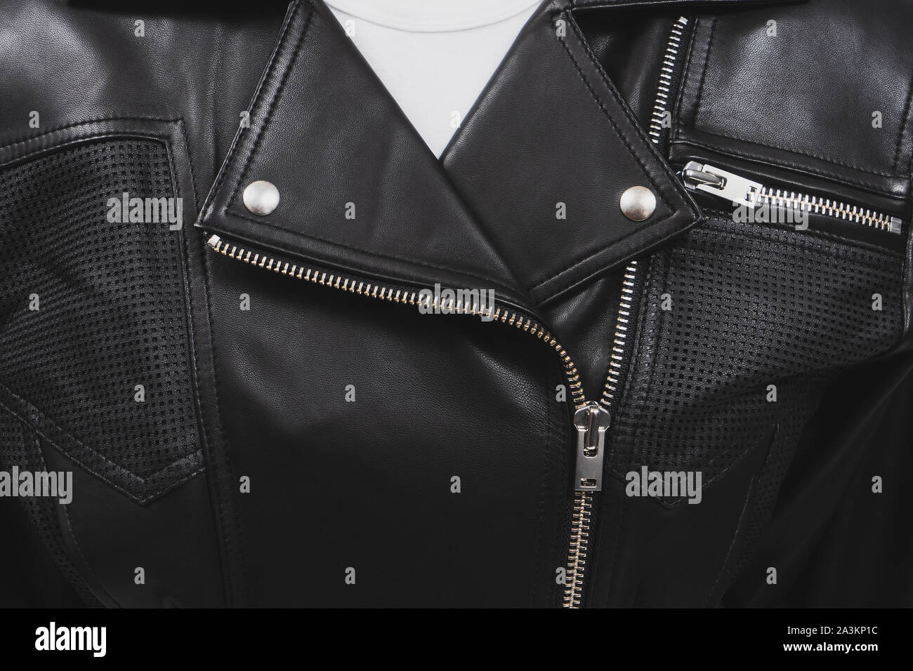 La chaqueta de cuero negro con elementos perforados. Cierres metálicos, cierres y botones. Ropa clásica para el ciclista. Acercamiento detallado. Camiseta blanca. Foto de stock