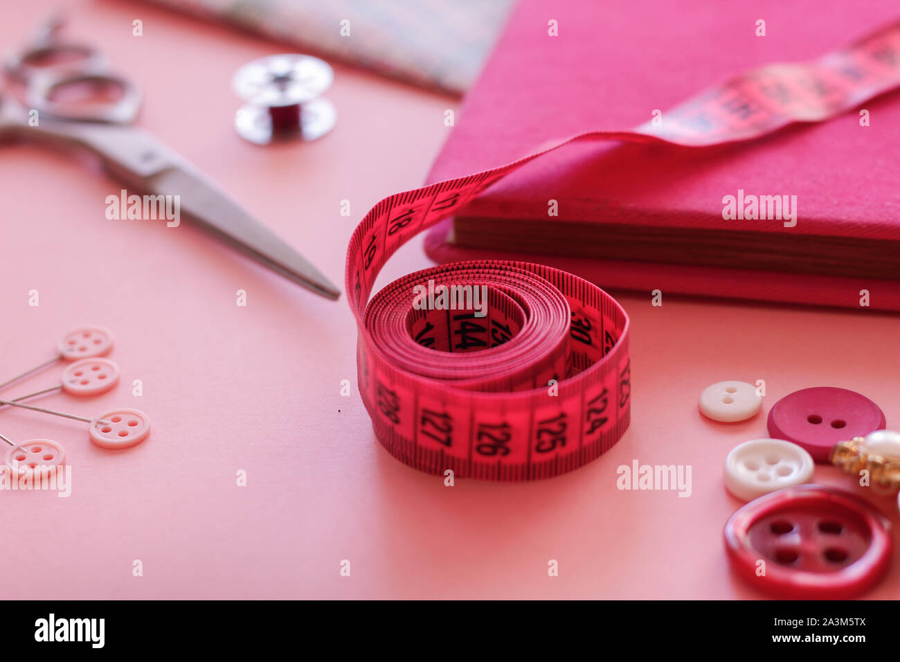 Medir la cinta en color rosa con otros objetos de costura Foto de stock