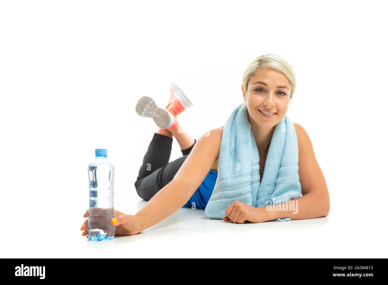 Mujer joven en sportswear con toalla alrededor de su cuello sosteniendo  botella de agua y sentado en la rueda grande para entrenamiento funcional  en el gimnasio Fotografía de stock - Alamy