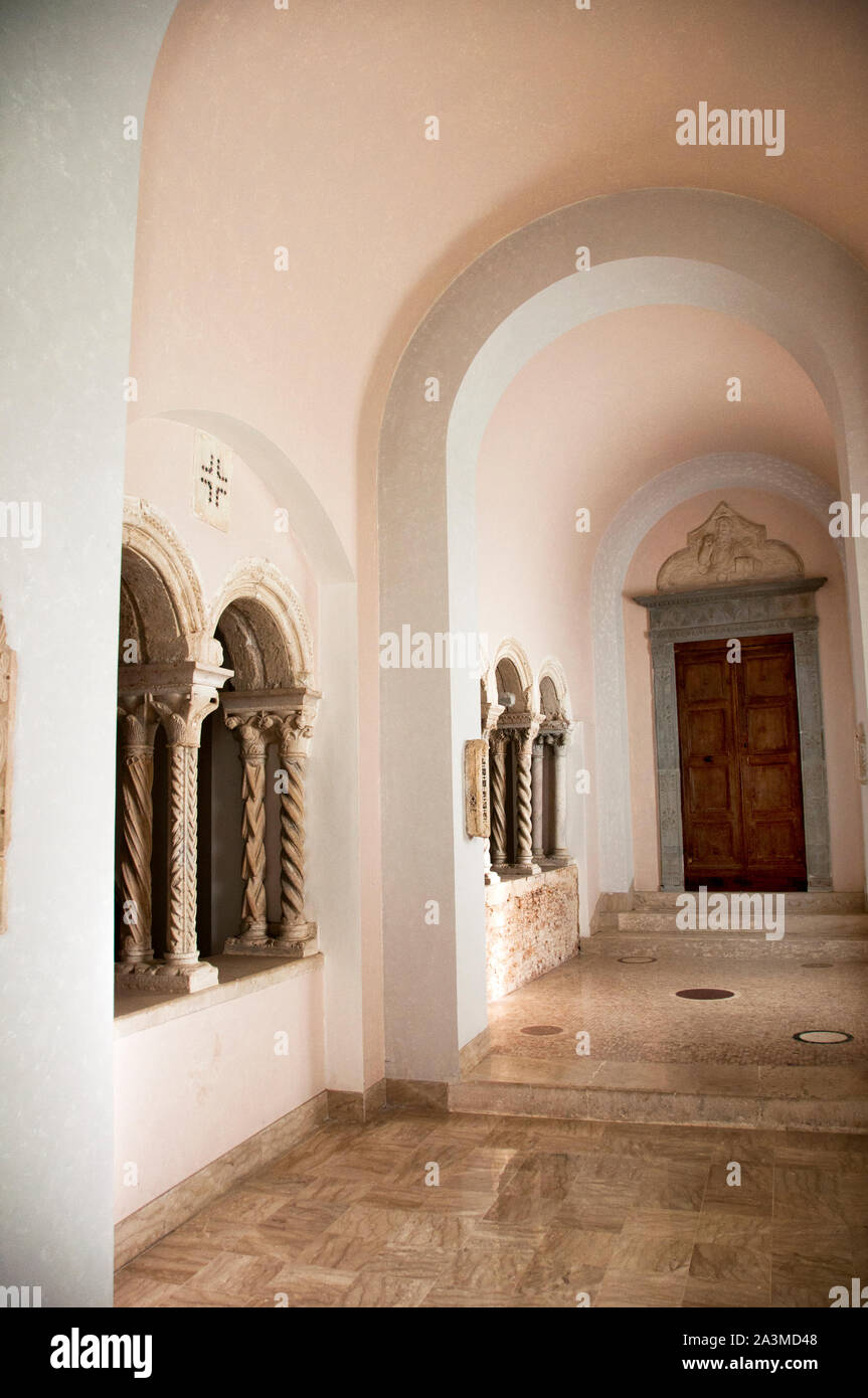 Pasillos interiores de arcos repetitivos y columnas retorcidas, la Abadía de Montecassino en Italia ofrece una transición cálida y ligera de un espacio a otro. Foto de stock