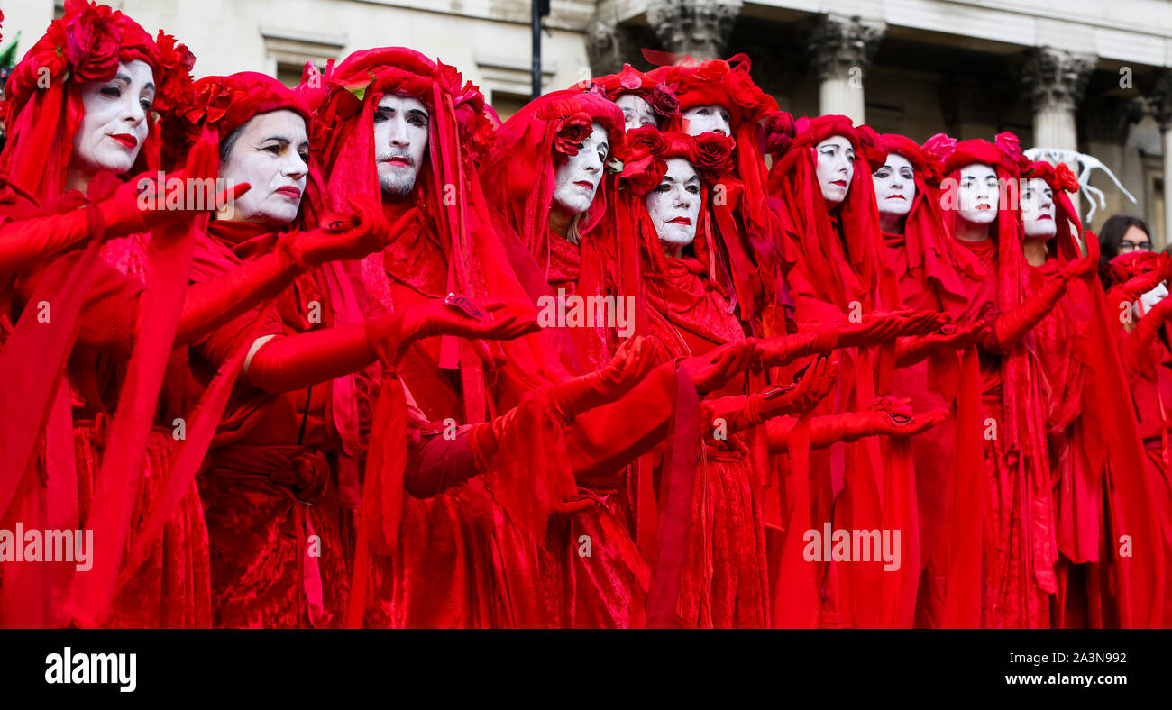 Los miembros de la Brigada Roja de la extinción movimiento de rebelión en sus trajes protestando en las escaleras de Trafalgar Square durante el tercer día de sus dos semanas de acción en Westminster. El cambio climático activistas están pidiendo al Gobierno del Reino Unido a adoptar medidas urgentes sobre el cambio climático. Foto de stock