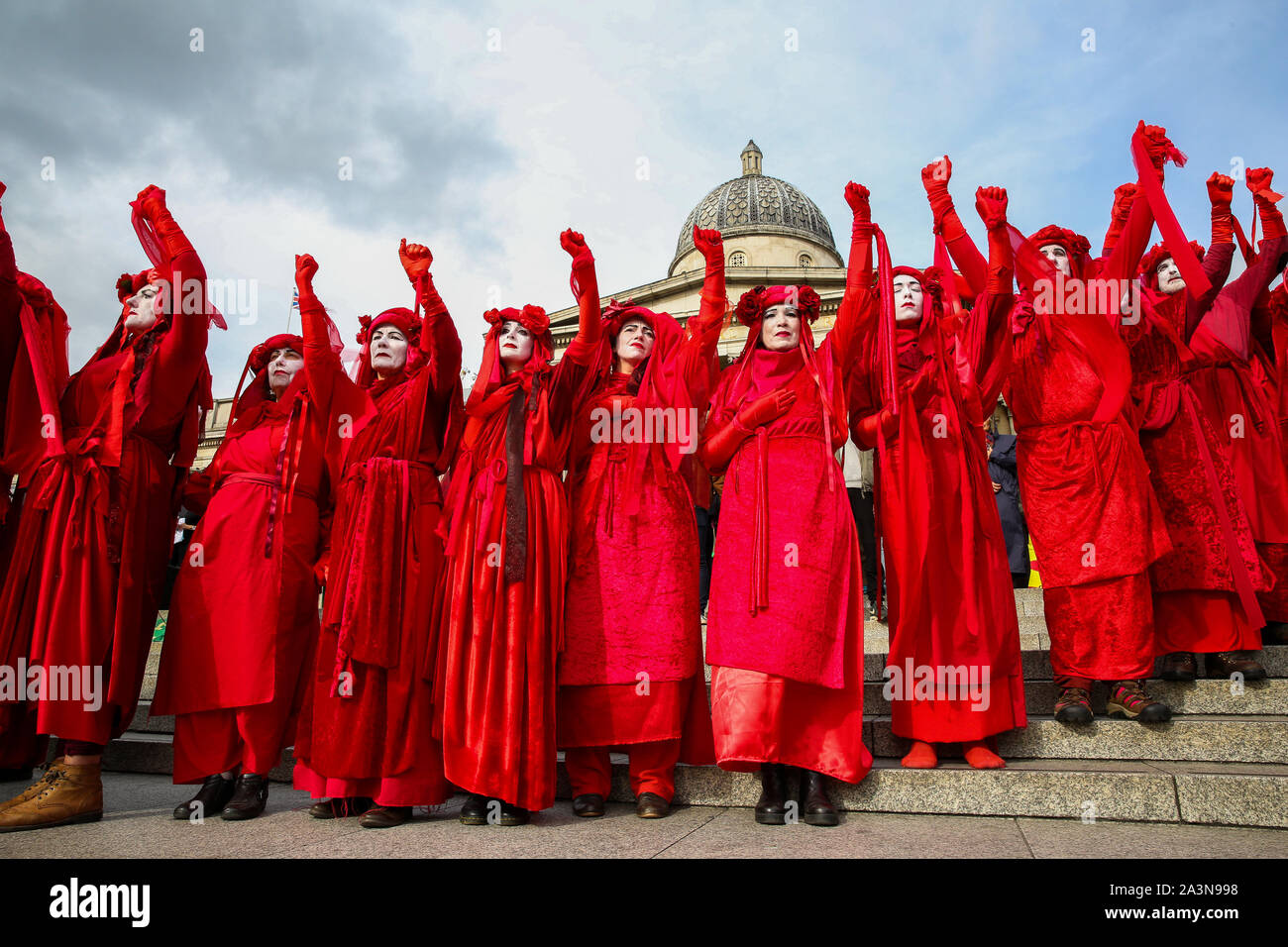 Los miembros de la Brigada Roja de la extinción movimiento de rebelión en sus trajes protestando en las escaleras de Trafalgar Square durante el tercer día de sus dos semanas de acción en Westminster. El cambio climático activistas están pidiendo al Gobierno del Reino Unido a adoptar medidas urgentes sobre el cambio climático. Foto de stock