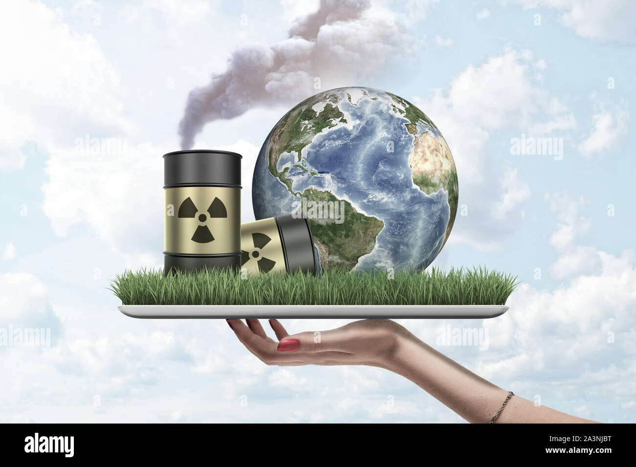 La mano que sostiene la mujer tableta digital con hierba verde, el planeta Tierra y dos barriles de desechos radiactivos coloca en pantalla, contra el cielo nublado. Foto de stock
