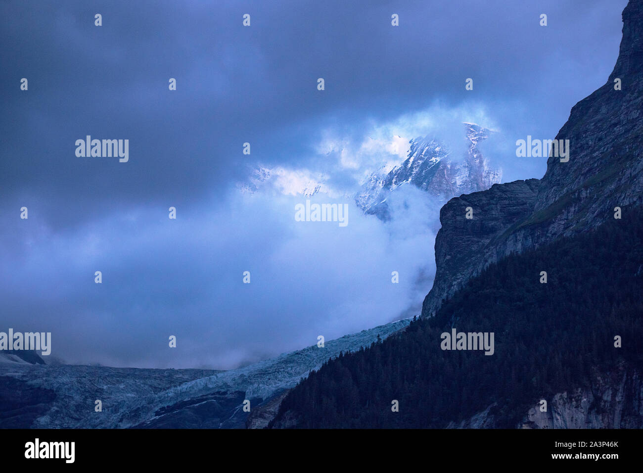 Vista panorámica del glaciar alpino en el atardecer. Cumbres nevadas detrás de las nubes. Cielo nublado. Paisaje alpino en la penumbra. Fiescherhorn, Suiza. Foto de stock