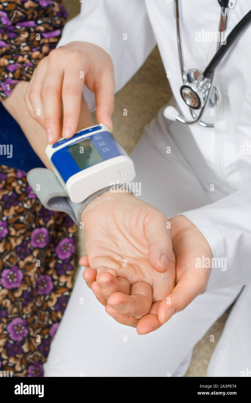 El médico medir la presión arterial de la mujer vieja Foto de stock