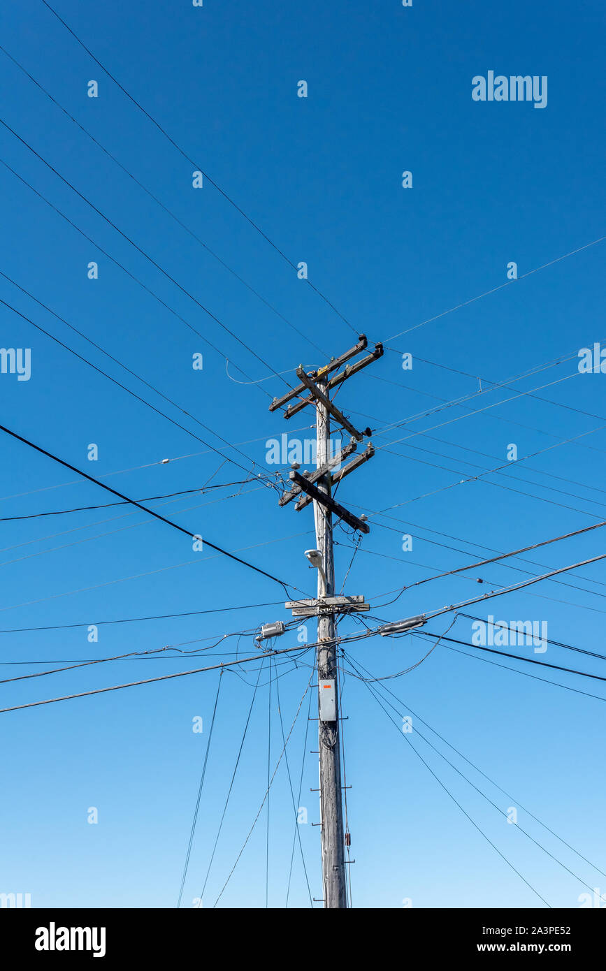 Muchas líneas de energía y cables de distribución de alta tensión incluyendo conectarse a lomos de un polo de energía de PG&E (poste telefónico) contra el cielo azul, la zona de Bay, California. Foto de stock