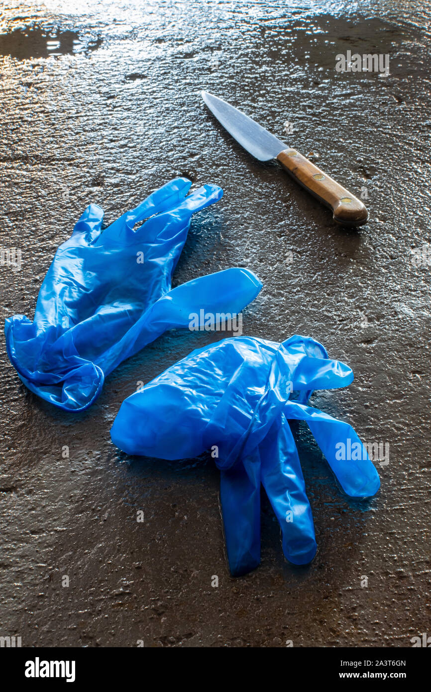 Guantes de látex azules y la cuchilla en el piso Foto de stock