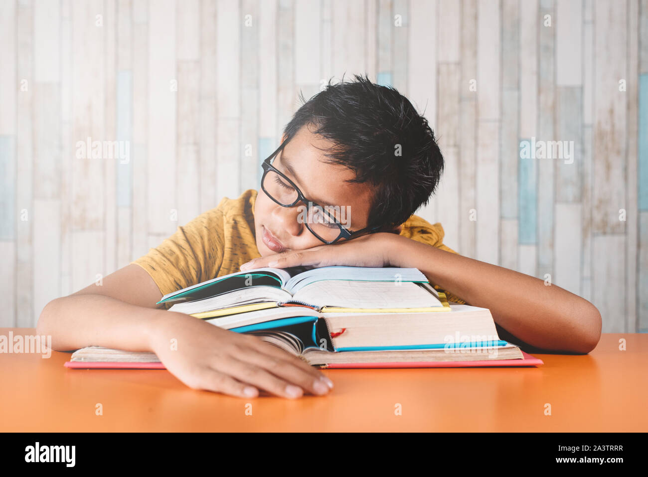 Joven estudiante varón asiático dormirse sobre una pila de libros mientras estudian. El concepto de educación, el cansancio y la pereza Foto de stock